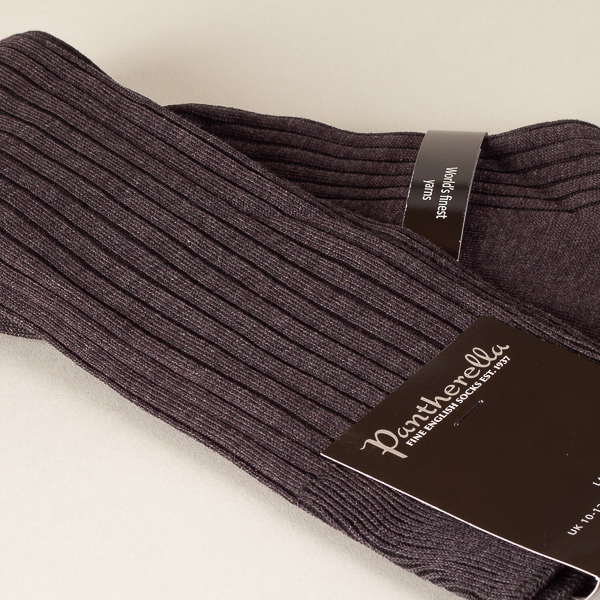 Een paar grijspaarse geribbelde sokken met de label "Pantherella FINE ENGLISH SOCKS EST. 1937" op een lichtbeige achtergrond.